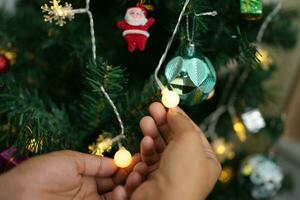 allegro Natale 2024 concetto asiatico donne decorare il Natale albero con colorato Natale palle. foto