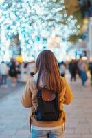 viaggiatore con Borsa visitare roppongi colline Natale illuminazione durante inverno stagione, contento turista donna sta su un' Natale mercato nel tokyo, Giappone. viaggiare, vacanza e celebrazioni concetto foto