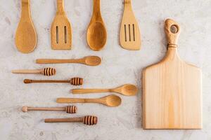 un' impostato di vario di legno cucchiai, spatole, taglio tavola fatto di eco-friendly materiale su un' leggero pietra controsoffitto. cucina sfondo. superiore Visualizza. foto