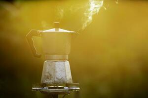 moka pentola e Fumo, vapore a partire dal il caffè pentola su fuoco, nel il foresta a Alba nel il mattina. morbido messa a fuoco. superficiale messa a fuoco effetto. foto