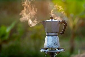 moka pentola e Fumo, vapore a partire dal il caffè pentola su fuoco, nel il foresta a Alba nel il mattina. morbido messa a fuoco. superficiale messa a fuoco effetto. foto