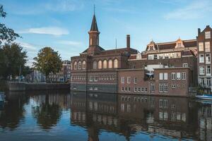storico edificio nel il centro di amsterdam riflette nel il calma acqua durante tramonto. Venezia di il nord. olandese storia foto