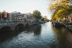 tramonto si illumina un' acqua canale e adiacente edifici nel il capitale città di amsterdam, il Olanda. Venezia di il nord foto