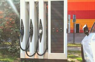 pubblico parcheggio con ev ricarica lungo il strada. eco elettrico veicolo ricarica stazione con energia cavo. fornitura tappato stazione, verde energia, blu potenza, alternativa energia, tecnologia e ev auto foto