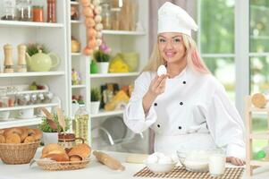 bellissimo giovane donna nel chef cappello cottura al forno a casa foto