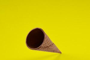 vuoto, delizioso wafer cono per ghiaccio crema contro giallo sfondo. concetto di cibo, tratta. modello, modello per il tuo pubblicità e design. vicino su foto