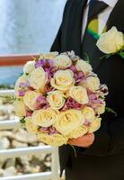 sposo alla moda che tiene un tenero bouquet da sposa rosa foto