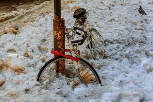 bicicletta sotto il neve, parcheggio su il strada foto