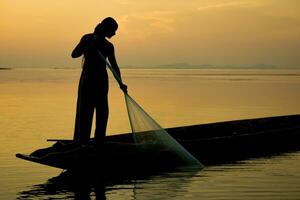 silhouette pescatore con tramonto cielo su il lago. foto