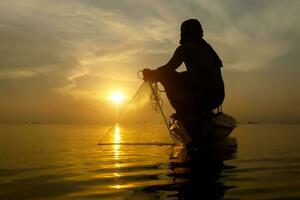 silhouette pescatore con tramonto cielo su il lago. foto