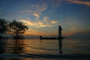 silhouette pescatore con tramonto cielo su il lago. foto