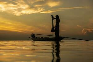 silhouette pescatore con tramonto cielo su il lago. foto