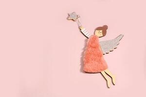 di legno angelo volante dietro a un' stella su un' rosa sfondo con copia spazio, festivo sfondo foto