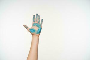 interno tiro di sollevato femminile braccio dimostrando palma dipinto con blu colore mentre in posa al di sopra di bianca sfondo. corpo linguaggio e gesti concetto foto