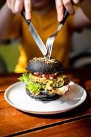 hamburger di quinoa al carbone con broccoli tagliati a mano con guacamole al coltello. foto