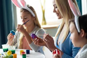 mamma e due bambini dipingono le uova di Pasqua. vista laterale. foto