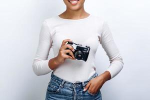 vista ravvicinata di una giovane donna che tiene una macchina fotografica su uno sfondo di muro bianco foto