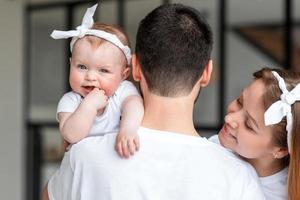 vista posteriore, padre che tiene in braccio la piccola figlia, moglie sorridente sinceramente felice. foto