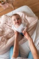 carino, bellissimo, piccolo bambino che gioca con la mamma, guardandola. concetto di cura, amore, protezione e affetto. foto