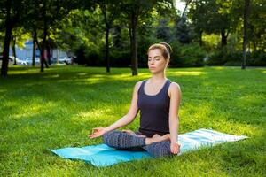 giovane donna fare yoga esercizi nel il estate città parco. foto