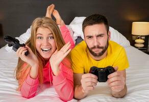 contento giovane coppia avendo divertimento giocando videogiochi nel letto foto