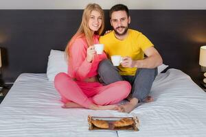 contento giovane coppia avendo prima colazione vassoio su letto a casa foto