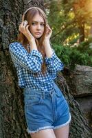 giovane donna carino brunetta ragazza in piedi vicino albero su cuffia, foto