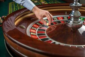 roulette ruota e croupier mano con bianca palla nel casinò foto