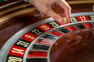 roulette ruota e croupier mano con bianca palla nel casinò foto