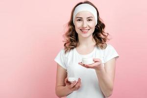 ragazza felice con una benda sulla testa tiene in mano un barattolo di crema idratante foto