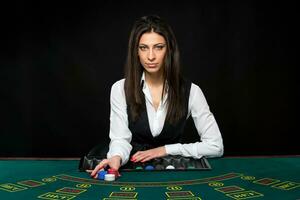 il bellissimo ragazza, rivenditore, dietro a un' tavolo per poker foto