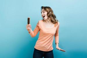 donna giocosa canta su un microfono che in realtà è una spazzola per capelli. foto