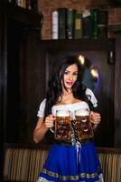 oktoberfest donna indossare un' tradizionale bavarese vestito dirndl in posa con un' birra boccale a bar foto