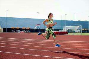 bellissimo giovane donna esercizio jogging e in esecuzione su atletico traccia su stadio. foto