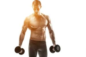 muscolare uomo mostrando Perfetto corpo con manubri, isolato su bianca foto