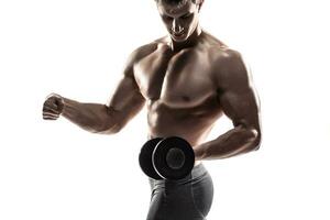 atletico uomo mostrando muscolare corpo e fare esercizi con manubri foto