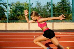 lato Visualizza bellissimo giovane donna esercizio jogging e in esecuzione su atletico traccia su stadio foto