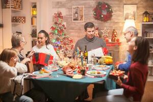 allegro donna dando sua madre un' presente a Natale famiglia cena. foto