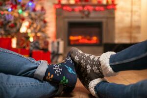 contento giovane coppia conservazione loro piedi insieme posa su il pavimento festeggiare Natale. foto