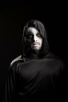 uomo con pauroso rendere su per Halloween indossare un' cappuccio isolato al di sopra di nero sfondo. foto