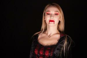 il male vampiro donna con biondo capelli al di sopra di nero sfondo. Halloween vestito. foto