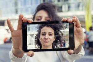 bella giovane donna prendere un' autoscatto con inteligente Telefono foto