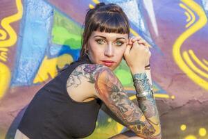 tatuato ribelle ragazza in posa contro un' parete dipinto foto