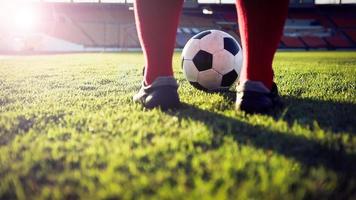giocatore di calcio o di calcio in piedi con la palla sul campo per calciare il pallone da calcio allo stadio di calcio