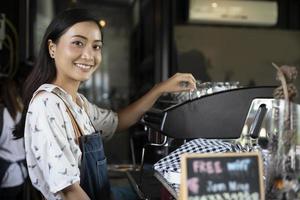 barista delle donne asiatiche che sorride e usa la macchina da caffè nel bancone della caffetteria - donna che lavora proprietario di una piccola impresa cibo e bevande concetto di caffè foto