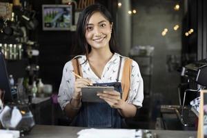 barista delle donne asiatiche che sorride e usa la macchina da caffè nel bancone della caffetteria - donna che lavora proprietario di una piccola impresa cibo e bevande concetto di caffè foto