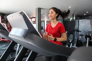 donne asiatiche che corrono scarpe sportive in palestra mentre una giovane donna caucasica sta facendo jogging sul tapis roulant foto