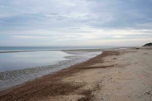 dune, nuvole, frangiflutti a riflusso marea su sabbioso spiaggia foto