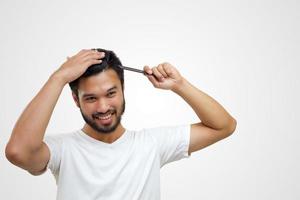 concetto di persone - giovane sorridente che spazzola i capelli con il pettine su sfondo bianco foto