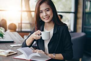 la donna d'affari asiatica sta lavorando e bevendo caffè in un momento di relax